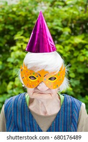 Portrait Of A Happy Elderly Woman Celebrating Birthday Outdoor, Wearing A Colorful Hat And Mask