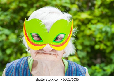 Portrait Of A Happy Elderly Woman Celebrating Birthday Outdoor, Wearing A Green Mask