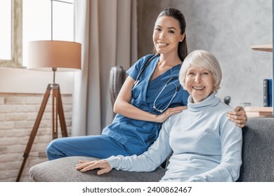 Portrait of happy elderly woman with nurse at home looking at camera, hugging embracing. Nursing house hospice, support and care, aiding seniors with lonely life - Powered by Shutterstock