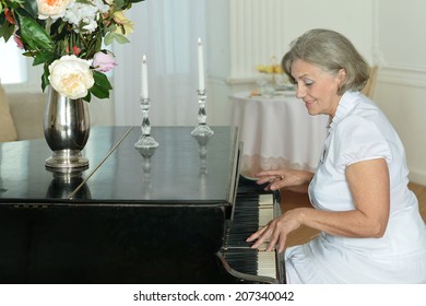 Portrait of happy elderly woman playing the piano at home