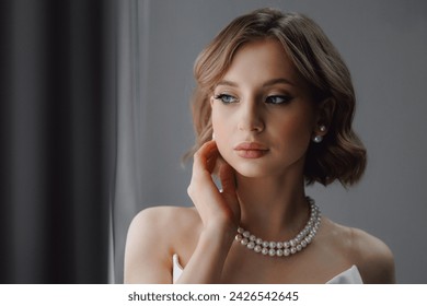 Portrait of happy elegant young woman in modern bridal look with classic hairstyle and makeup with pearl necklace. - Powered by Shutterstock