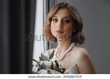 Portrait of happy elegant young woman in modern bridal look with classic hairstyle and makeup hold white rose bouquet.