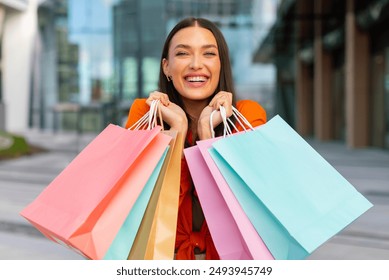 Portrait of happy European woman posing with lots of shopping bags, holding colored paper packages, enjoying weekend sales. Commerce and discounts - Powered by Shutterstock