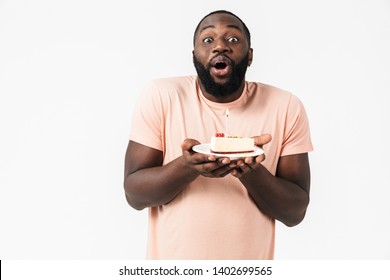 Portrait of a happy excited african man wearing shirt standing isolated, holding plate with birthday cake