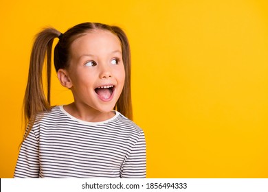 Портрет счастливого взволнованного изумленного открытого рта ребенка девочки выглядит в копировальном пространстве, изолированном на желтом фоне