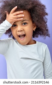 Portrait Of Happy Excited Amazed Open Mouth Kid Child Girl Look At Camera Cheerfully Isolated On Purple Color Background. Cheerful Curly Black Kid In White Shirt Is Surprised. Children, Human Emotions