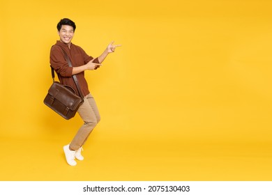 Portrait Of Happy Excited Asian Man Office Worker Pointing Hands To Empty Space On Isolated Yellow Background, Full Body Composition And Looking At Camera