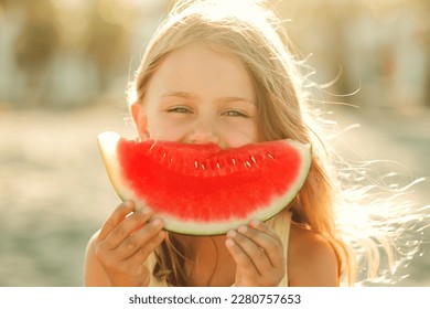 Portrait happy excited funny child little girl eat piece of juice watermelon on beach. Concept of summertime and picnic outdoors. Banner, copy space, place fot text,isolated. Nature background