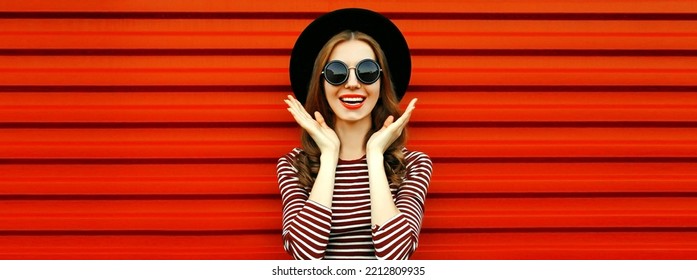 Portrait Of Happy Excited Young Woman Wearing Black Round Hat And Sunglasses On Red Background