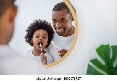 Porträt von glücklicher Familie schwarz afrikanischen Vater und Sohn Kind Jungen Putzzähne im Badezimmer. Morgenprogramm mit Zahnbürsten, Tageskonzept des Vaters