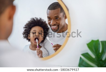 Portrait of happy family black African American father and son child boy brushing teeth in the bathroom. Morning routine with toothbrushes, father’s day concept Foto stock © 