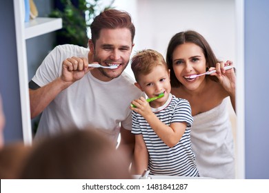 Portrait Of Happy Family Brushing Teeth In The Bathroom