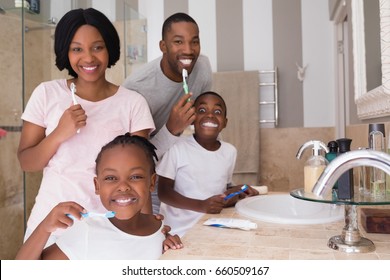 Portrait Of Happy Family Brushing Teeth In Bathroom At Home