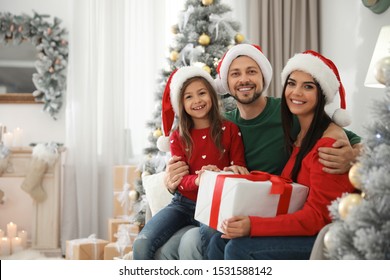 Portrait Of Happy Family With Christmas Gift At Home, Space For Text