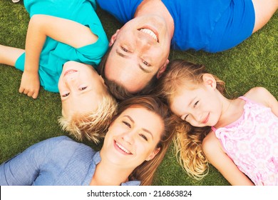 Portrait Of Happy Family Of Four Outside On The Grass