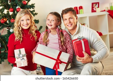 Portrait Of Happy Family With Giftboxes Looking At Camera On Christmas Day