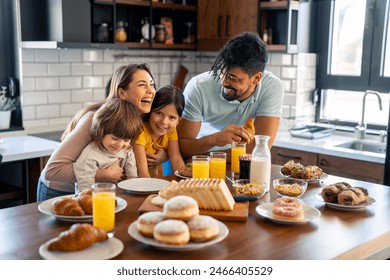 Portrait of happy family having breakfast. Parents laughing with their children at the table. - Powered by Shutterstock