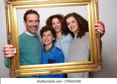 Portrait Of A Happy Family Holding Picture Frame And Smiling