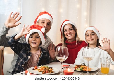 Portrait Of Happy Family Looking At Camera During Vegan Christmas Dinner Party Wearing Santa Claus Hats - Focus On Little Son