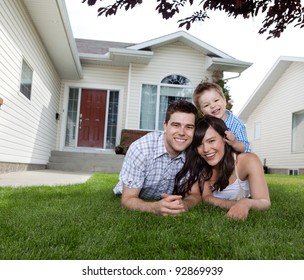 Portrait of happy family lying down on grass in front of house