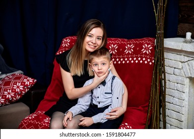 Portrait Of A Happy Family: Mom And A Cute Boy 10 Years Old Schoolboy At Home On The Sofa In A Loft Style. Sitting Right In Front Of The Camera, Showing Emotions, Smile