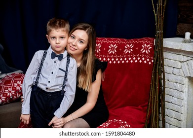 Portrait Of A Happy Family: Mom And A Cute Boy 10 Years Old Schoolboy At Home On The Sofa In A Loft Style. Sitting Right In Front Of The Camera, Showing Emotions, Smile