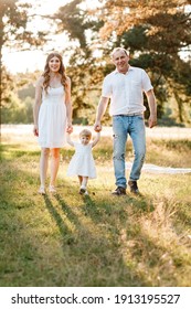 Portrait Of Happy Family. Mom, Dad And Daughter Walk In The Park In Nature. Young Family Spending Time Together On Vacation, Outdoors. The Concept Of Summer Holiday. Mother's, Father's, Baby's Day