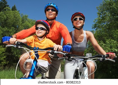 Portrait Of Happy Family On Bicycles In The Park