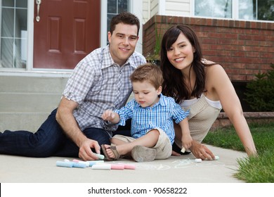 Portrait Of Happy Family Playing Outside House On Sidewalk