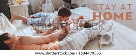 Relaxed mother and sons playing over the bed