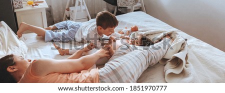 Similar – Relaxed mother and sons playing over the bed