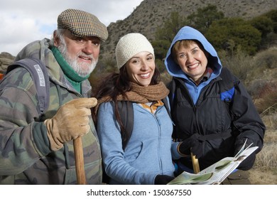 Portrait Of Happy Family With Poles And Map Hiking Together In Desert