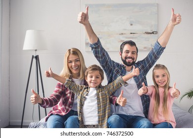 portrait of happy family showing thumbs up and looking at camera at home - Powered by Shutterstock