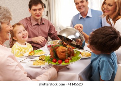 Portrait of happy family sitting at festive table and holding each other by hands