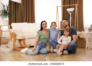 Portrait of happy family sitting on floor in new house. Moving day