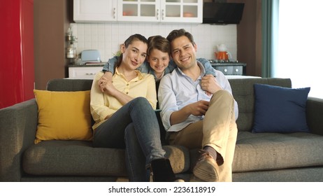 Portrait of happy family sitting on sofa in their peaceful home. Parents smiling at camera with their little cute preschool son. - Powered by Shutterstock