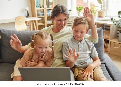 Portrait Of Happy Family With Special Needs Child Waving At Camera While Enjoying Video Chat With Relatives