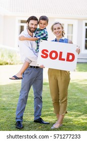 Portrait Of Happy Family Standing Outside Home With Sold Sign