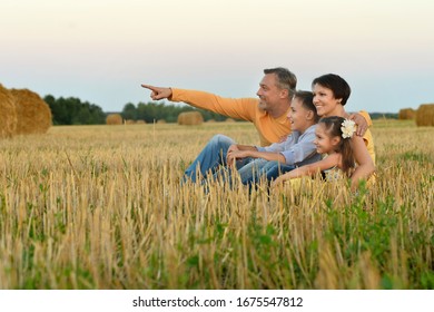 Portrait of happy family in summer field. man pointing with finger - Shutterstock ID 1675547812