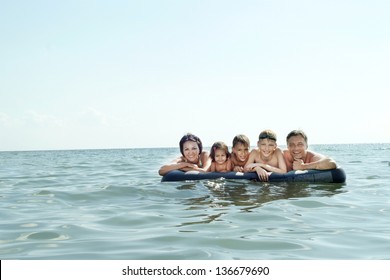 Portrait Of A Happy Family Swimming On An Air Mattress