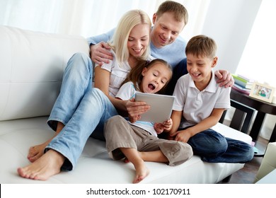 Portrait of happy family with two children sitting on sofa - Powered by Shutterstock