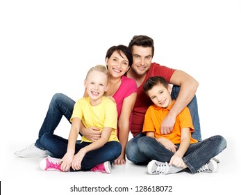 Portrait of the happy  family with two children sitting at studio on white floor