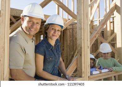 Portrait of happy family wearing hardhats at their incomplete house