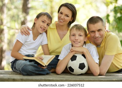 Portrait Of Happy Family At Wooden Table With Football Ball And Book