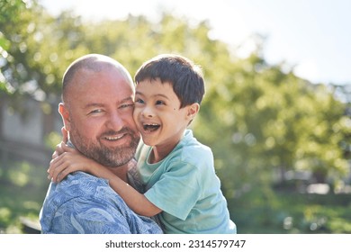 Portrait happy father holding cute son with down syndrome in summer backyard - Powered by Shutterstock