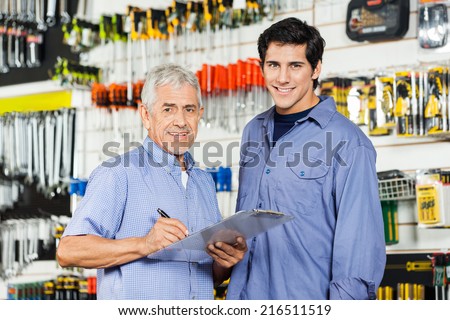Portrait of happy father and son preparing checklist in hardware store