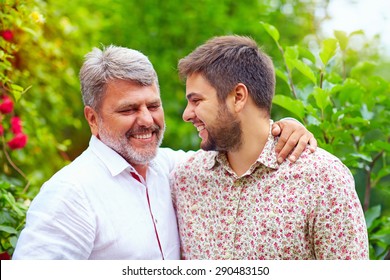 Portrait Of Happy Father And Son Talking Outdoors. Like Father Like Son