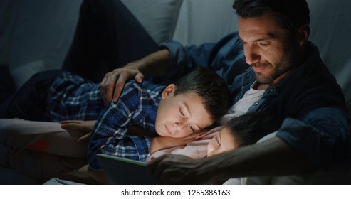 Portrait of happy father and son using a tablet on sofa in the evening in slow motion. Concept of family entertainment, education, technology - Powered by Shutterstock