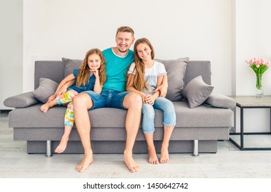 Portrait of happy father with two adorable smiling daughters on the couch - Shutterstock ID 1450642742