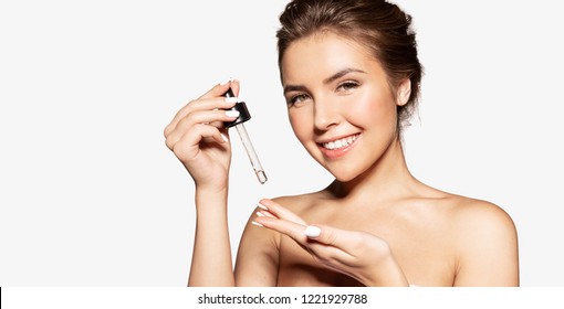 Portrait Of Happy Female Applying Cosmetic Oil On Hand. Sincere Smile Of Pretty Woman Posing In Studio. Beauty Skincare Concept. Isolated On Grey Background